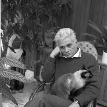 Imagen en blanco y negro de un hombre con un gato en sus brazos Descripción generada automáticamente con confianza media