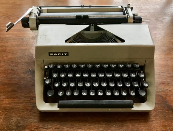 Máquina de escribir sobre una superficie de madera Descripción generada automáticamente con confianza media
